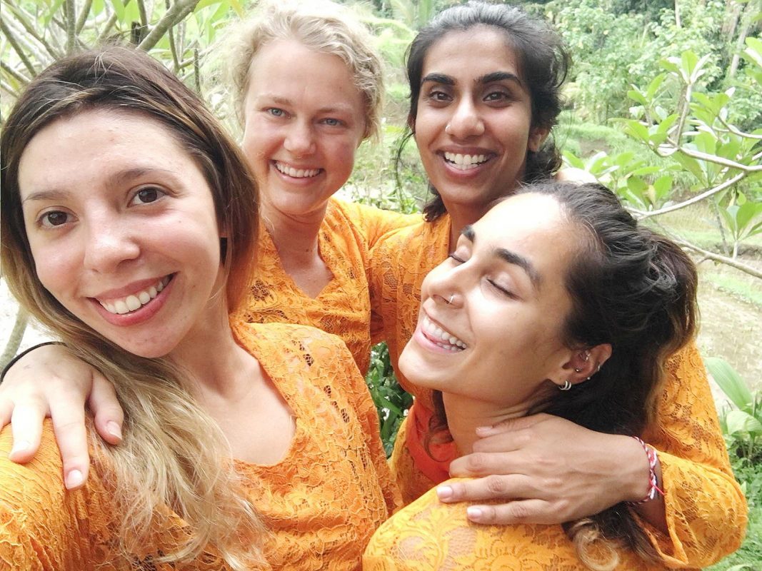 4 vrouwen in oranje kleding tijdens yoga teacher training 